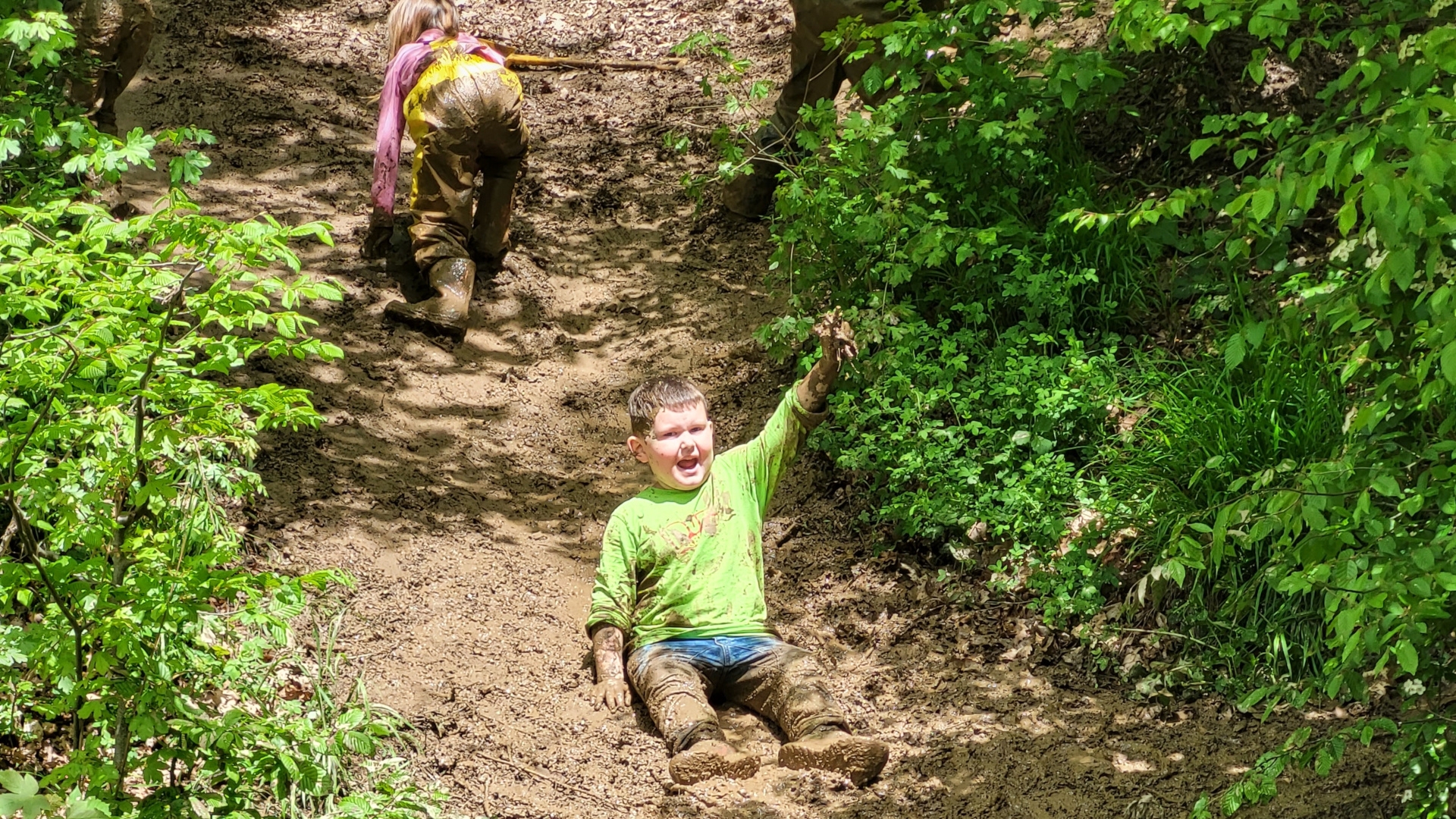 Das Foto zeigt einen Jungen, der auf der Hangrutsche rutscht und darüber ein Mädchen, dass gerade den Berg hinaufklettert.