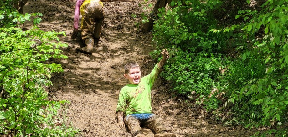 Das Foto zeigt einen Jungen, der auf der Hangrutsche rutscht und darüber ein Mädchen, dass gerade den Berg hinaufklettert.
