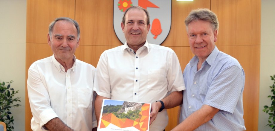 Das Foto zeigt von links nach rechts den Kreisbeigeordneten Peter Simon, Alexander Hauck und Oberbürgermeister Frank Frühauf, die gemeinsam einen der Bildungsordner in die Kamera halten.