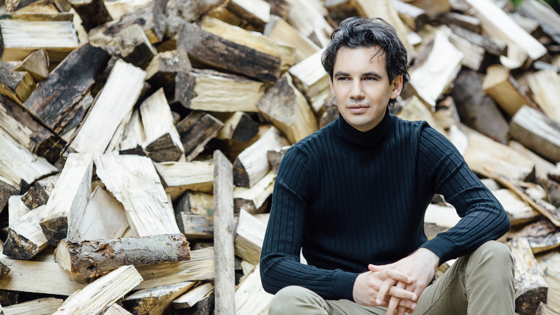 Das Foto zeigt Martin Stadtfeld vor einem Holzstapel.