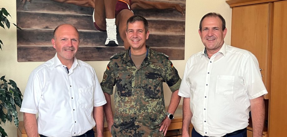 Das Foto zeigt von rechts nach links Oberbürgermeister Frank Frühauf, Oberst Olaf Tuneke und Bürgermeister Friedrich Marx, die im Büro von OB Frühauf vor einer Wand mit einem Gemälde stehen und in die Kamera schauen.