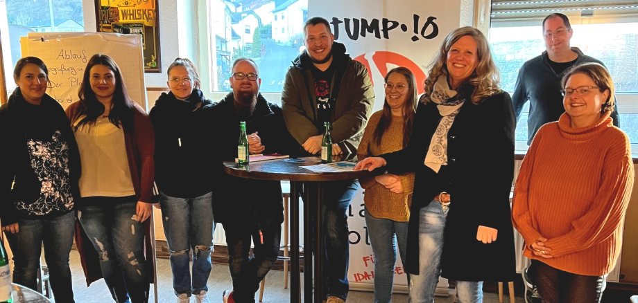Das Foto zeigt neun Teilnehmer des Treffens an einem Stehtisch.