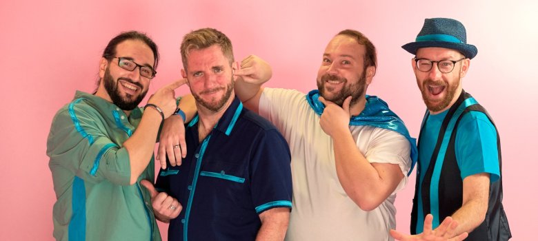 Pelemele Das Foto zeigt die vier Musiker der Band Pelemele vor einem bunten Hintergrund.