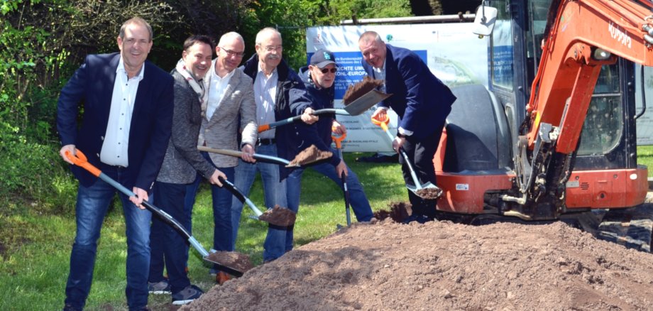 Das Foto zeigt von links nach rechts Oberbürgermeister Frank Frühauf, Ratsmitglied Frank Schnadhorst, den technischen Bauamtsleiter Dirk Thomé, die Ratsmitglieder Wolfgang Röske und Armin Korpus sowie den Bundestagsabgeordneten Dr. Joe Weingarten die mit Spaten an einem Erdhügel stehen. 