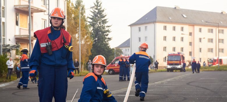 Das Foto zeigt drei Mitglieder der Jugendfeuerwehr die mit Schläuchen eine Wasserversorgung installieren.