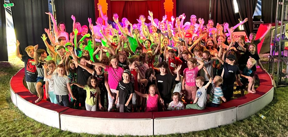 Das Foto zeigt ein Gruppenbild der Kinder, Betreuer und Besucher in der Manege.