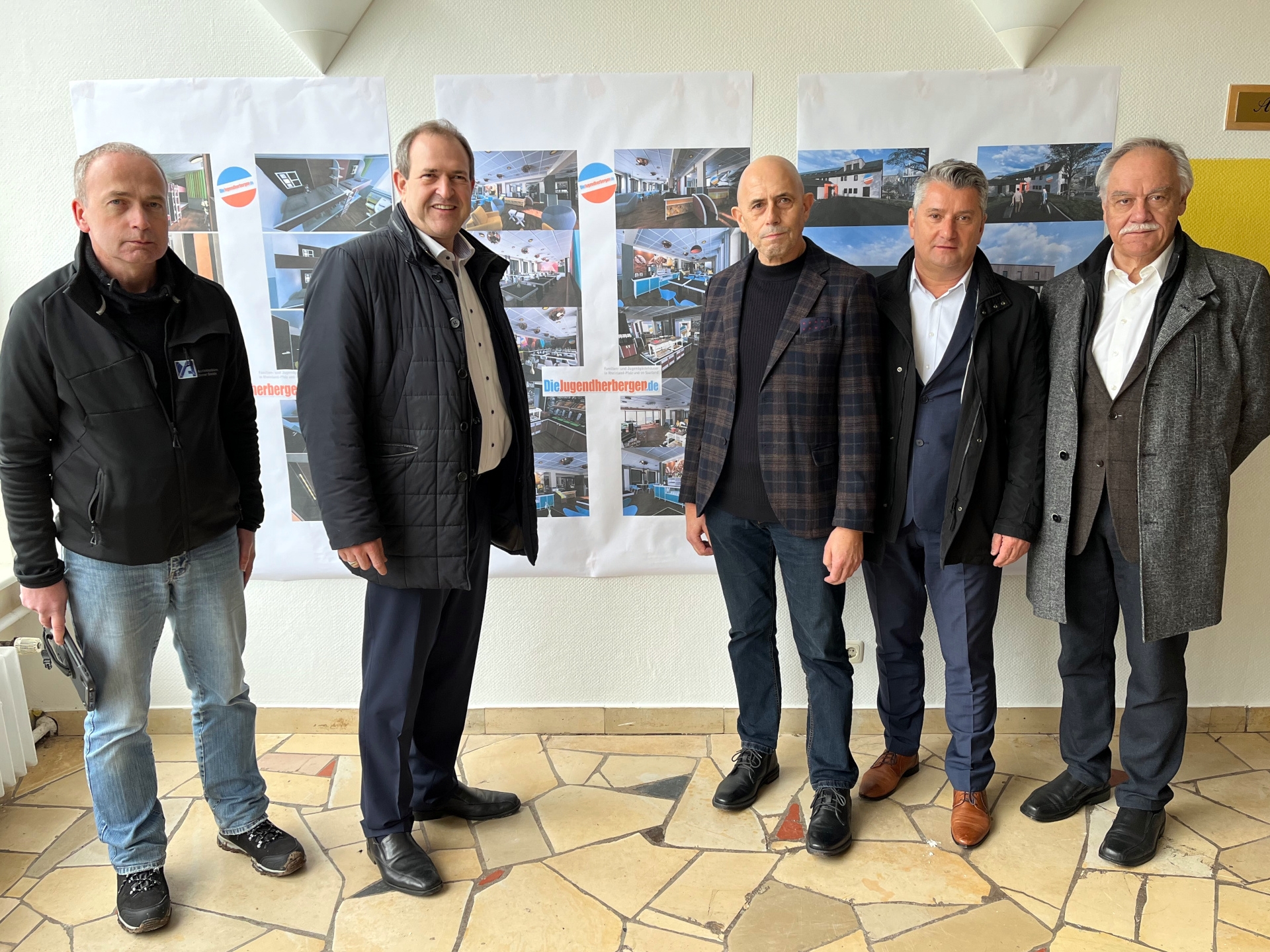 Das Foto zeigt die genannten Personen. Sie stehen nebeneinander vor einer Wand, an der die großformatigen Fotos hängen und schauen in die Kamera.