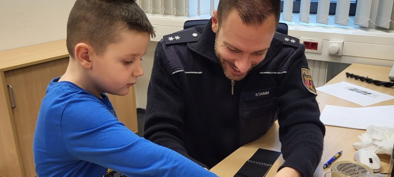 Das Foto zeigt einen Polizisten, der einem der Kinder einen Fingerabdruck abnimmt.
