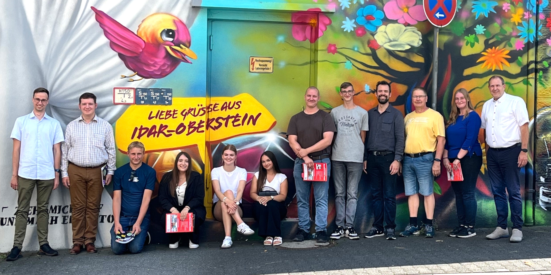 Das Foto zeigt die Azubis und Vertreter der Verwaltung an dem neuen Fotopoint am Bahnhof Idar-Oberstein.
