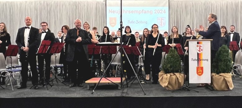 Das Foto zeigt das gesamte Orchester, das mit dem Dirigenten auf der Bühne steht. Der Oberbürgermeister steht am Rednerpult und applaudiert den Preisträgerinnen und Preisträgern.