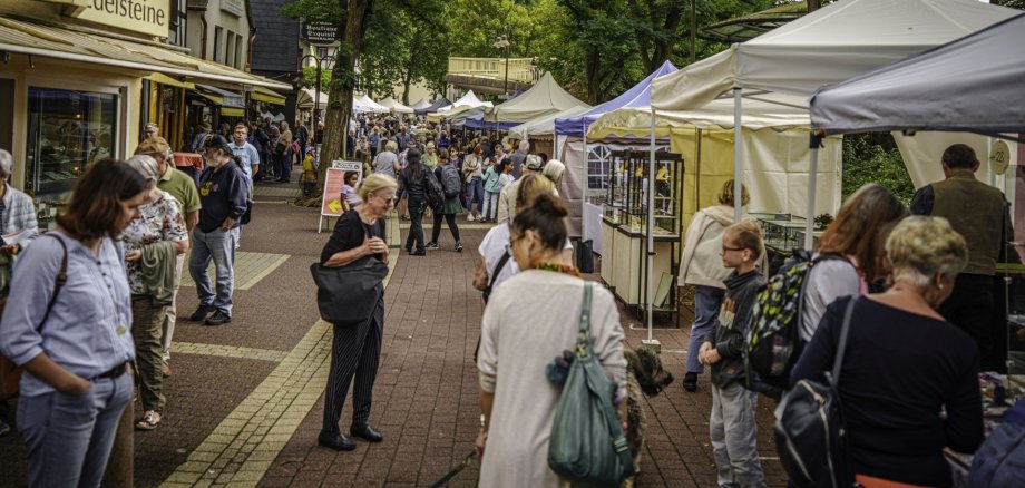 Das Foto zeigt einen Blick auf die Hauptstraße im Stadtteil Oberstein während des Edelsteinschleifer- und Goldschmiedemarktes. Zu sehen sind viele Menschen die durch die Straße gehen bzw. vor den Pavillons der Aussteller stehen.
