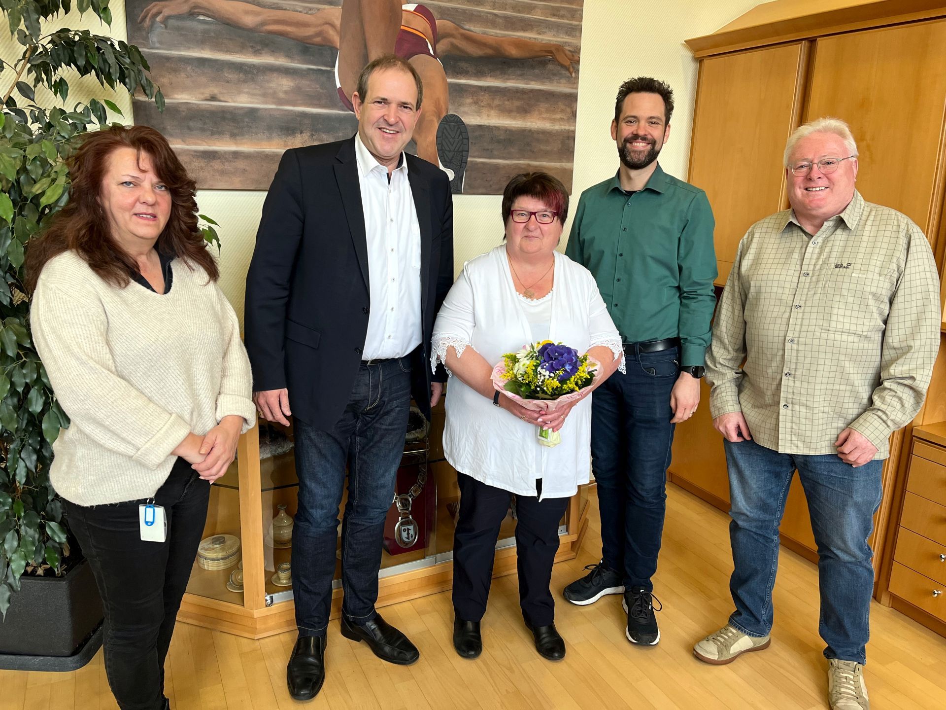 Das Bild zeigt Christiane Mernberger, die verabschiedet wird, den Oberbürgermeister und Kollegen. 