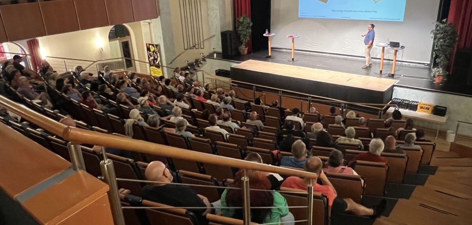 Das Foto zeigt den unteren Bereich des Theatersaals im Stadttheater, der für die Informationsveranstaltung gut besetzt ist. 