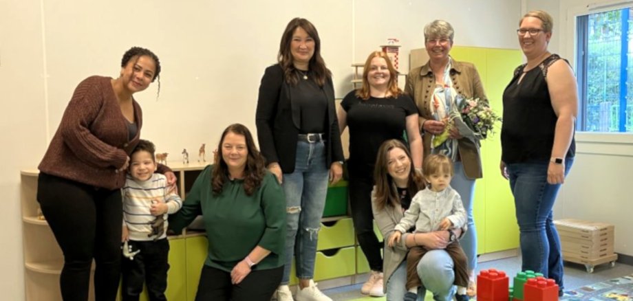Das Foto zeigt die genannten Personen. Sie stehen nebeneinander in einem Raum der Kita und blicken in die Kamera.