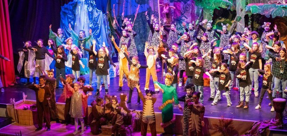 Das Bild zeigt im Finale alle Darsteller des Stückes Rummel im Dschungel auf der Bühne. 