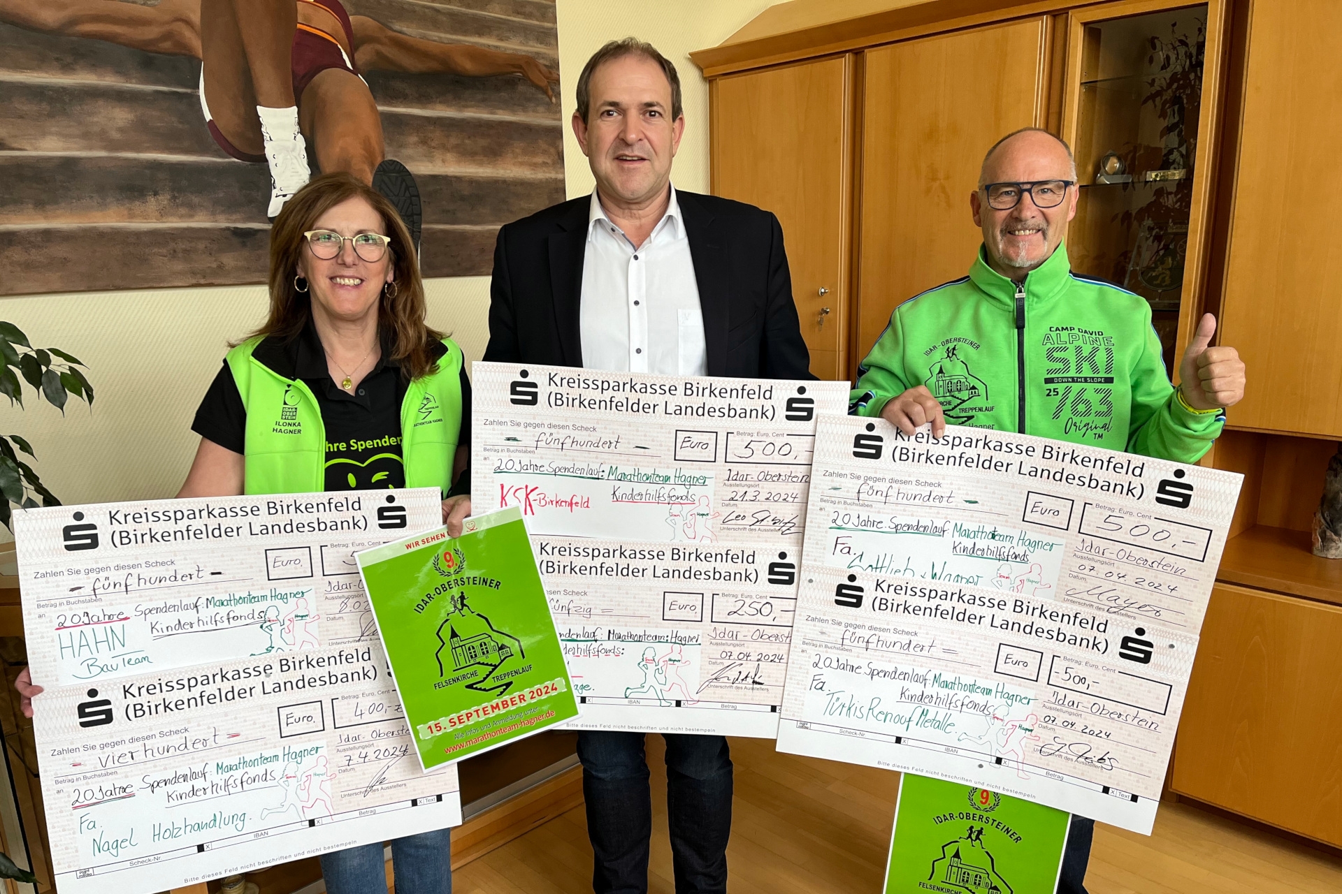 Das Foto zeigt die genannten Personen. Sie stehen nebeneinander im Büro des Oberbürgermeisters, halten Spendenschecks in den Händen und schauen in die Kamera.