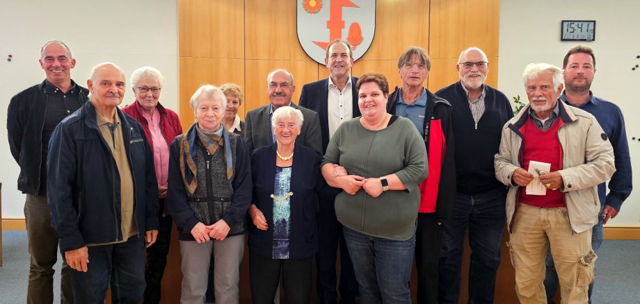 Das Foto zeigt die Mitglieder des Seniorenbeirates. Sie stehen im Sitzungssaal in zwei Reihen vor dem Vorstandstisch und schauen in die Kamera.