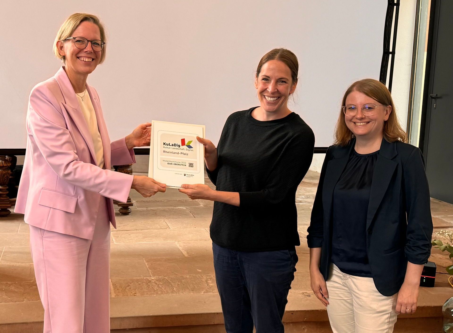 Isabelle Hahn von der Tourist-Information und Archivarin Dr. Svenja Müller mit Staatssekretärin Simone Schneider im Rahmen des diesjährigen Netzwerktreffens der KuLaDig Modellkommunen.