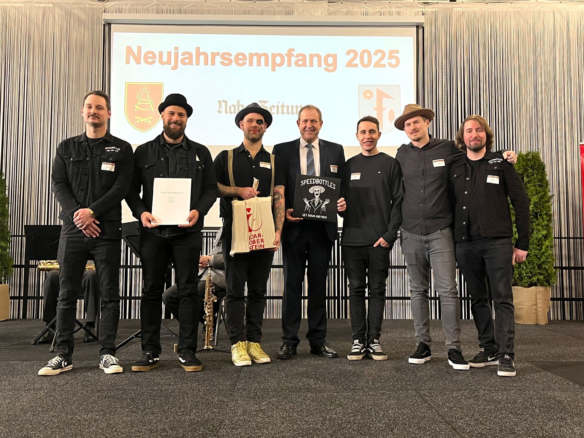 Das Foto zeigt die Musiker der SpeedBottles mit Oberbürgermeister Frühauf auf der Bühne bei der Preisverleihung. 