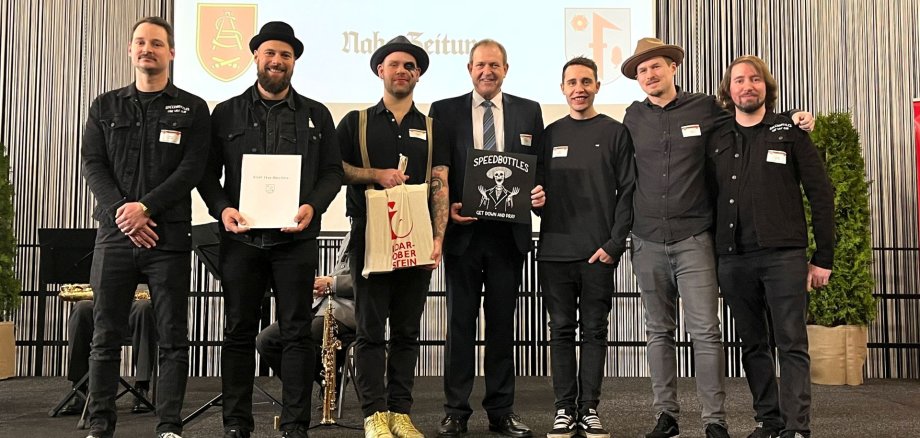 Das Foto zeigt die Musiker der SpeedBottles mit Oberbürgermeister Frühauf auf der Bühne bei der Preisverleihung. 