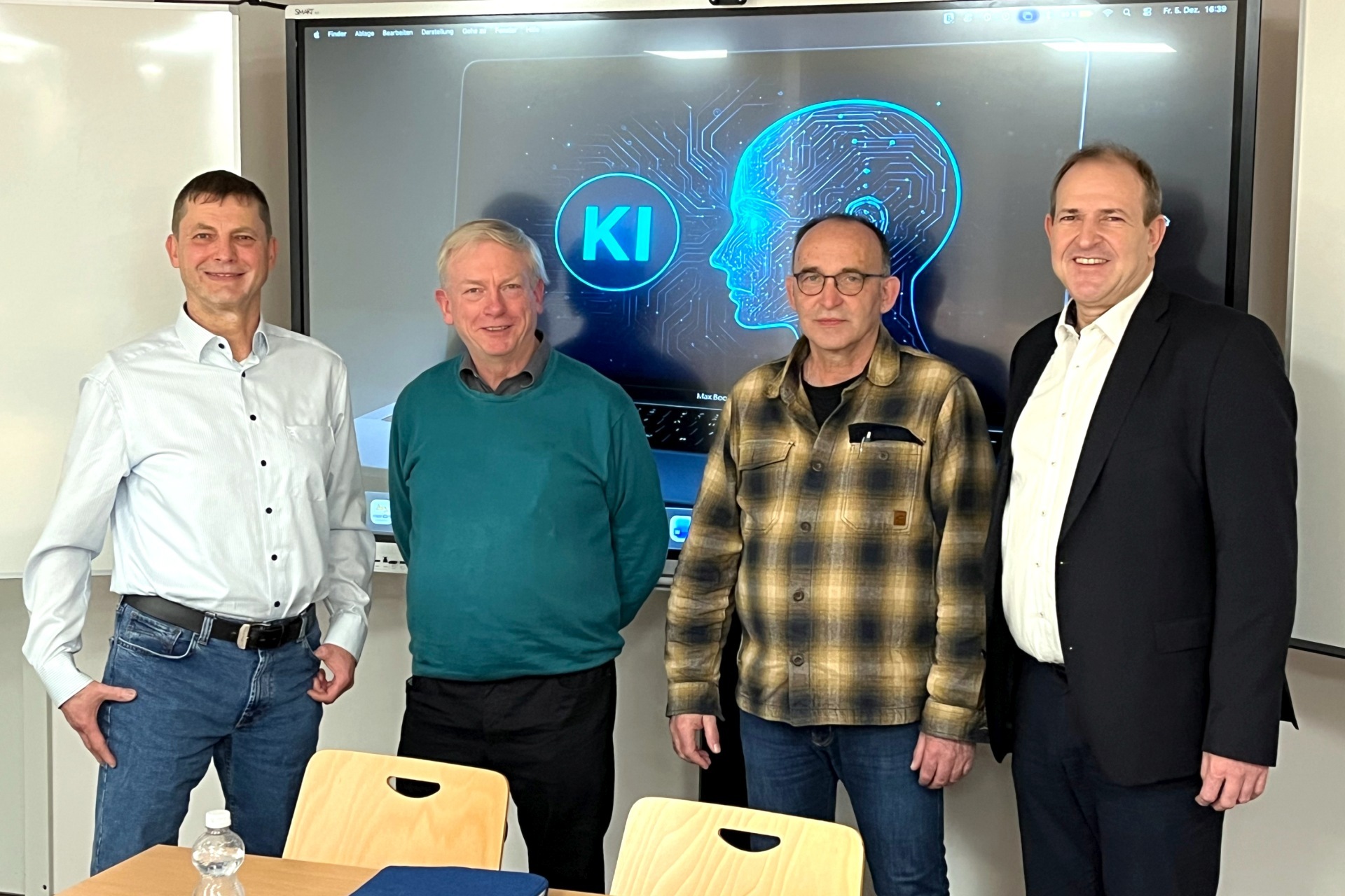 Das Foto zeigt die genannten Personen, die nebeneinander vor dem Bildschirm im Medienraum stehen und in die Kamera schauen.