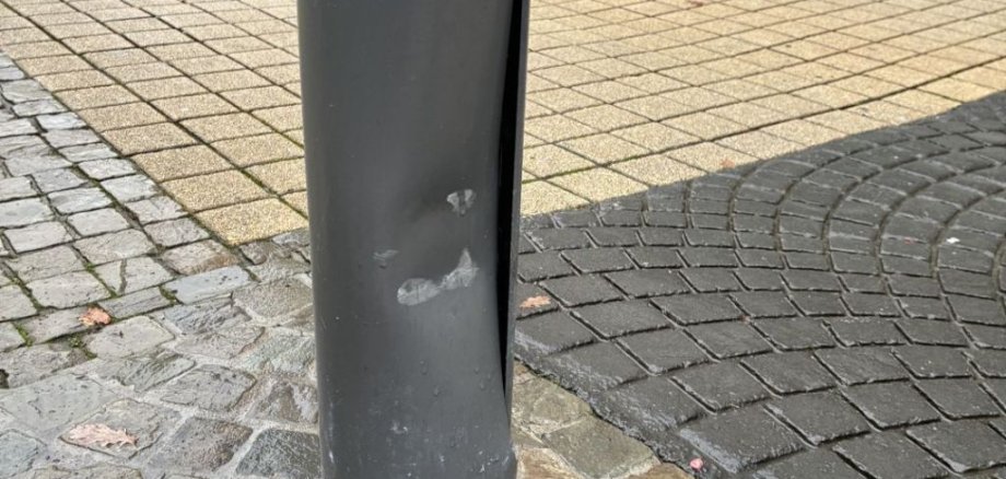 Das Foto zeigt einen Lichtmast, der einen Schaden durch einen Unfall hat. 