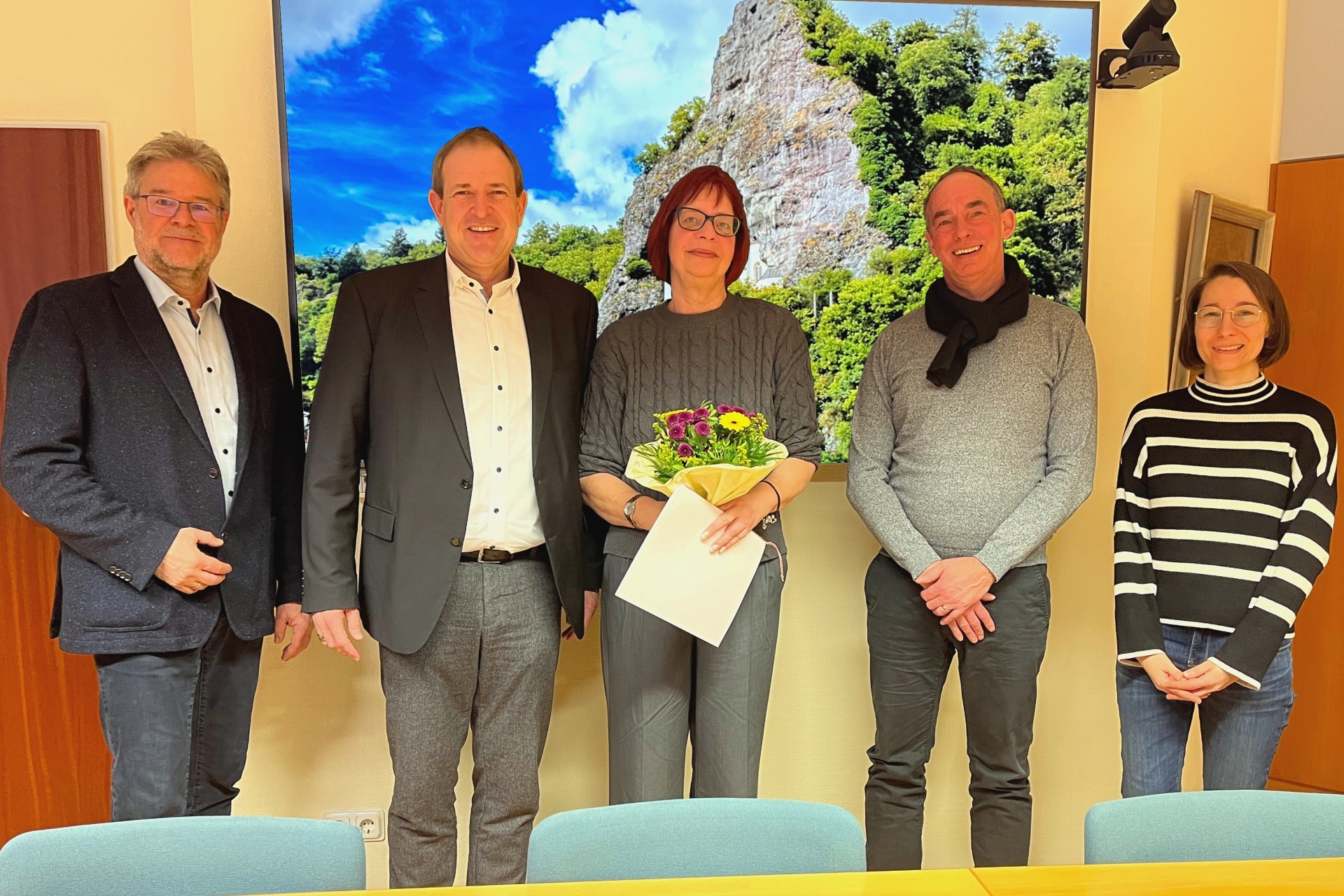 Das Foto zeigt fünf Personen, die nebeneinander stehen und in die Kamera schauen. Frau Schöfferle steht in der Mitte und hält einen Blumenstrauß in der Hand.