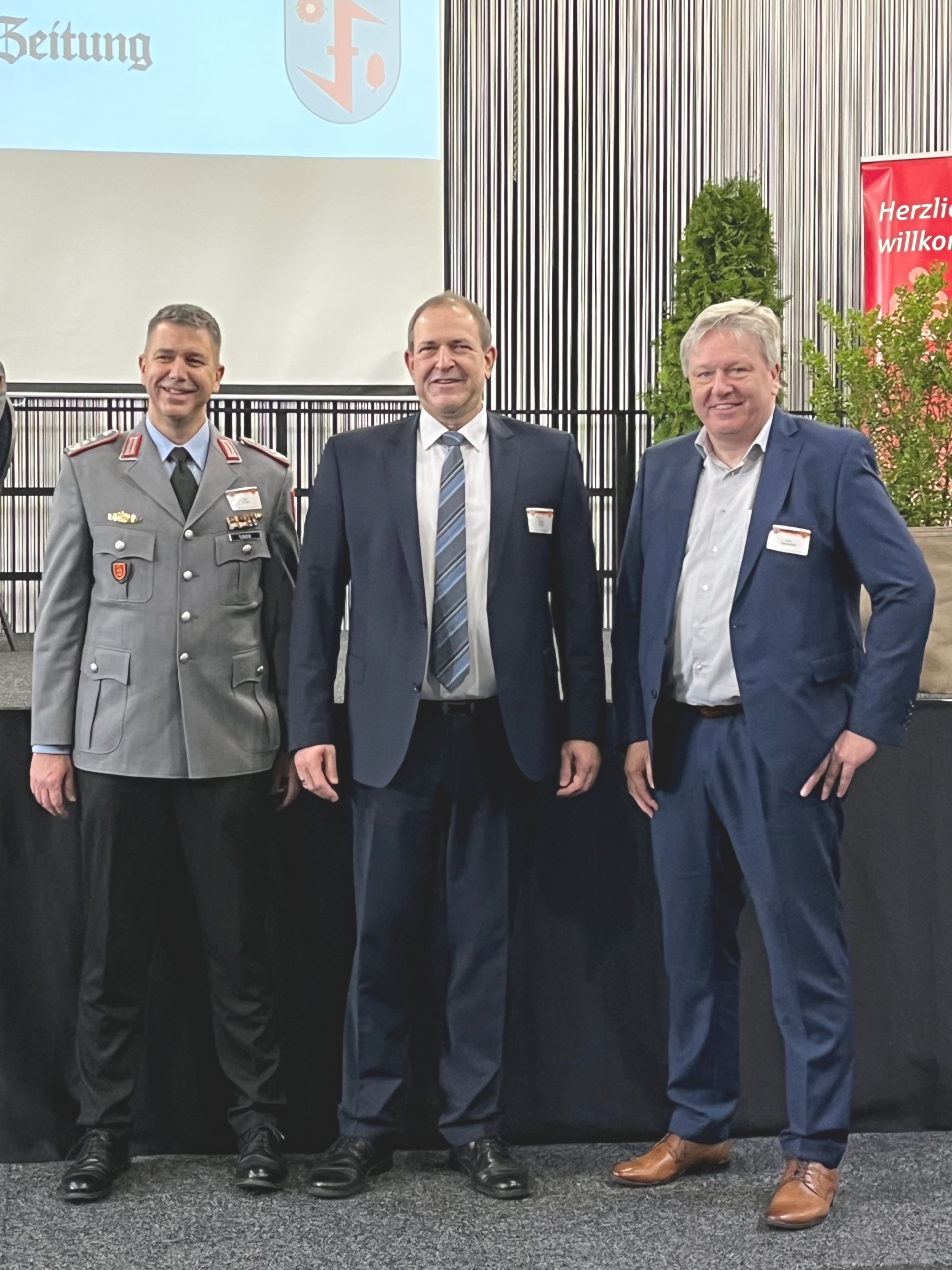 Das Foto zeigt die genannten Personen, die vor der Bühne stehen.