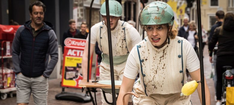 Straßentheater mit den Soap Sisters Das Foto zeigt die Soap Sisters, die mit BMX Rädern durch die Besucher fahren und eine Spüle dabei haben.