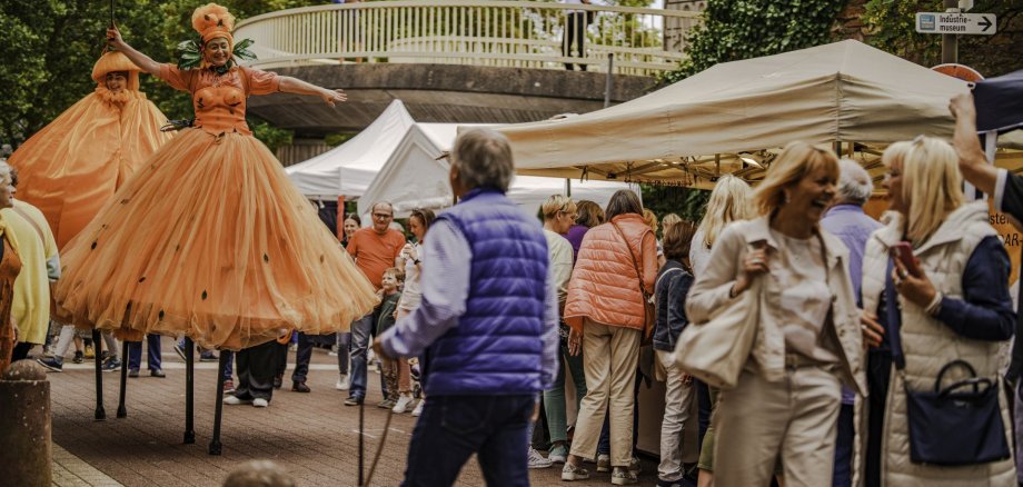 Das Foto zeigt einen Walk-Act der Orangen auf Stelzen darstellt. 