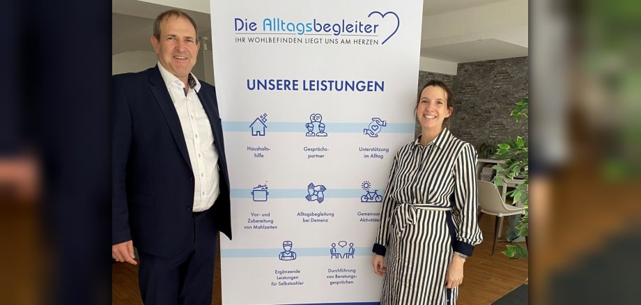 Das Foto zeigt Oberbürgermeister Frank Frühauf und die Geschäftsführerin Selina Dorow neben einem Roll-Up der Alltagsbegleiter. 