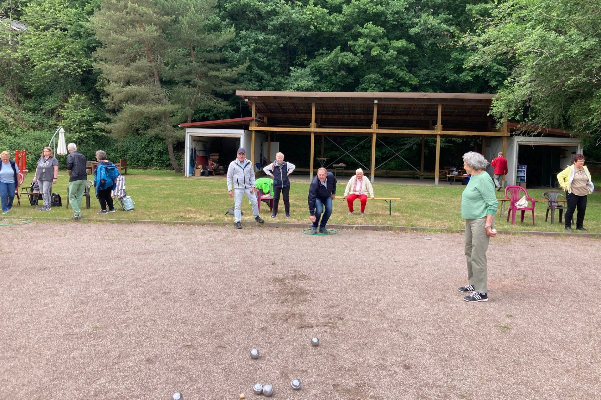Das Foto zeigt einige Personen beim Boule-Spielen auf dem Familiensportplatz.