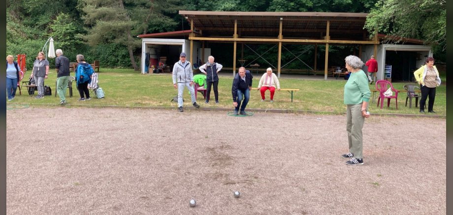Das Foto zeigt einige Personen beim Boule-Spielen auf dem Familiensportplatz.