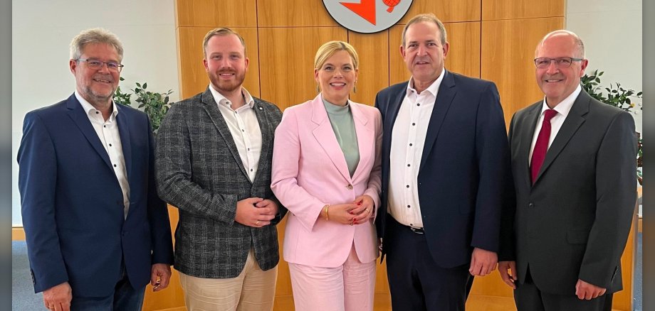 Das Foto zeigt die genannten Personen. Sie stehen im Sitzungssaal nebeneinander und schauen in die Kamera.