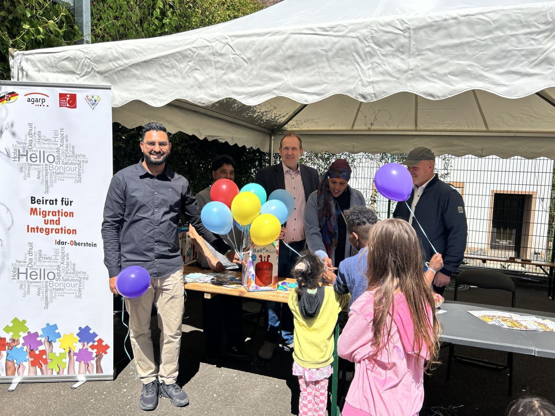 Arslan Muneeb, Vorsitzender BMI, Shahid SOHAIL, 2. Stellv. Vorsitzender BMI, OB Frank Frühauf, Bariga Hussein Ali, 1. Stellv. Vorsitzende BMI sowie Bürgermeister Friedrich Marx sowie Gäste des Festes. Auf dem Foto sind Mitglieder des Beirates für Migration und Integration, die die Integreat-App vorgestellt haben an einem Stand auf dem Wasenfest.