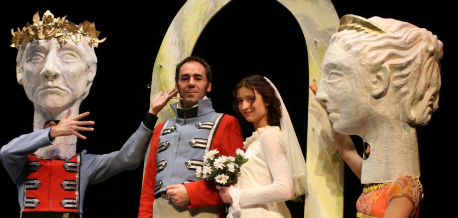 Das Foto zeigt eine Spielszene mit zwei Personen die heiraten möchten und zwei weiteren mit Masken. 
