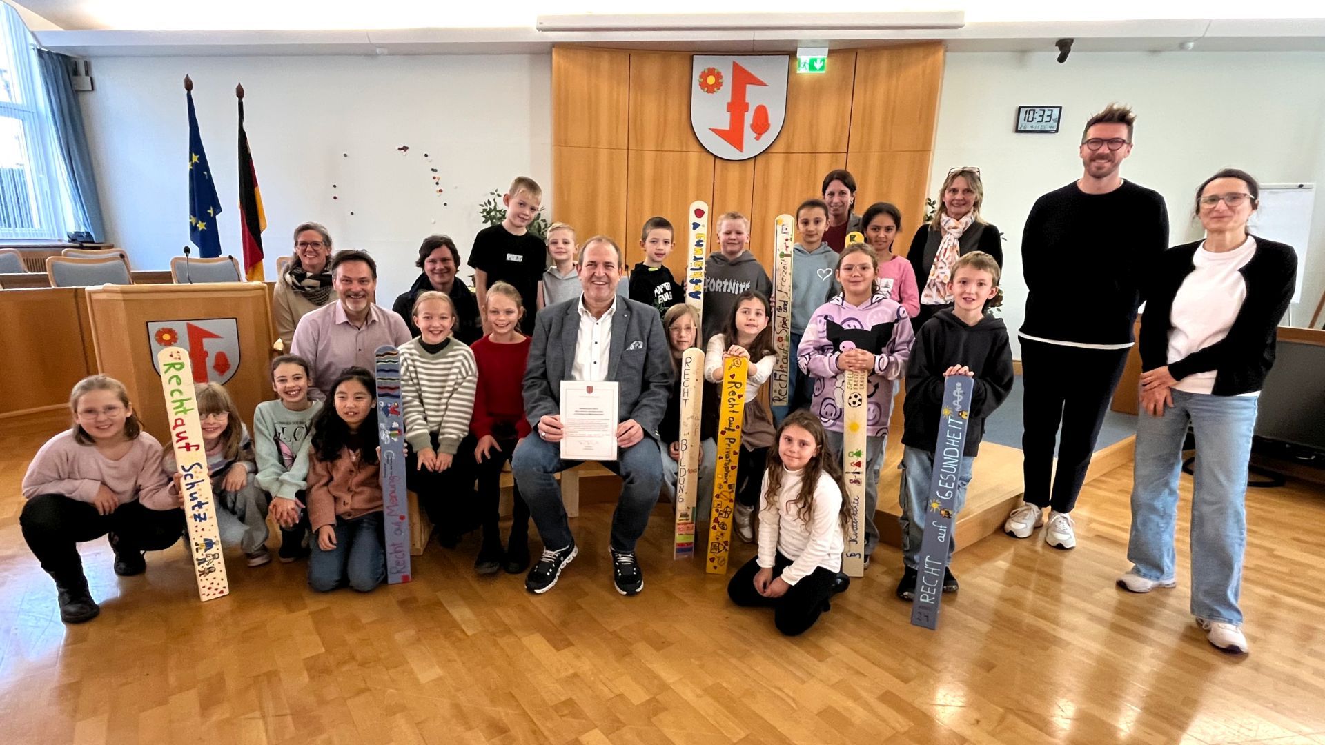 Das Foto zeigt die Kinder der Grundschule Göttschied mit dem Oberbürgermeister und Vertretern von Jugendamt und Schule im Sitzungssaal bei der Übergabe. 