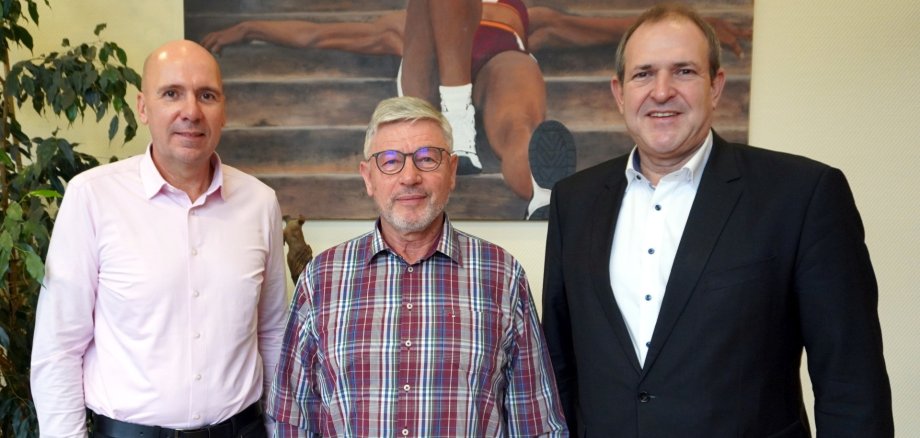 Das Foto zeigt die genannten Personen, die im Büro des Oberbürgermeisters vor einem Bild stehen und in die Kamera schauen.