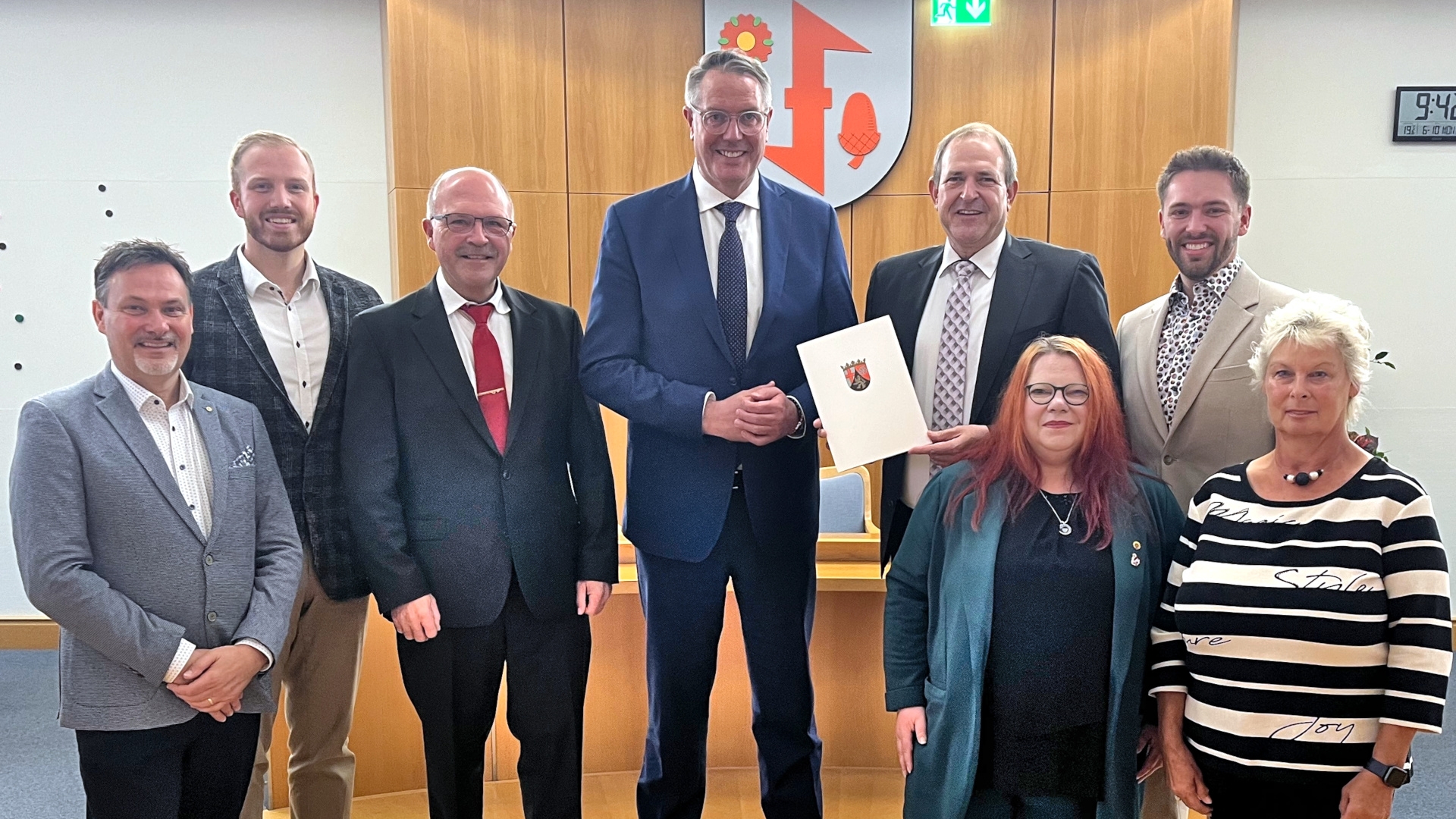Das Foto zeigt die genannten Personen, sie stehen nebeneinander im Sitzungssaal. OB Frühauf hält den Förderbescheid in der Hand.
