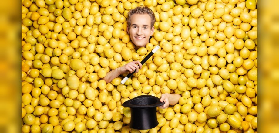 Das Foto zeigt Linus Faber mit Zauberstab und Zylinder inmitten von Zitronen.