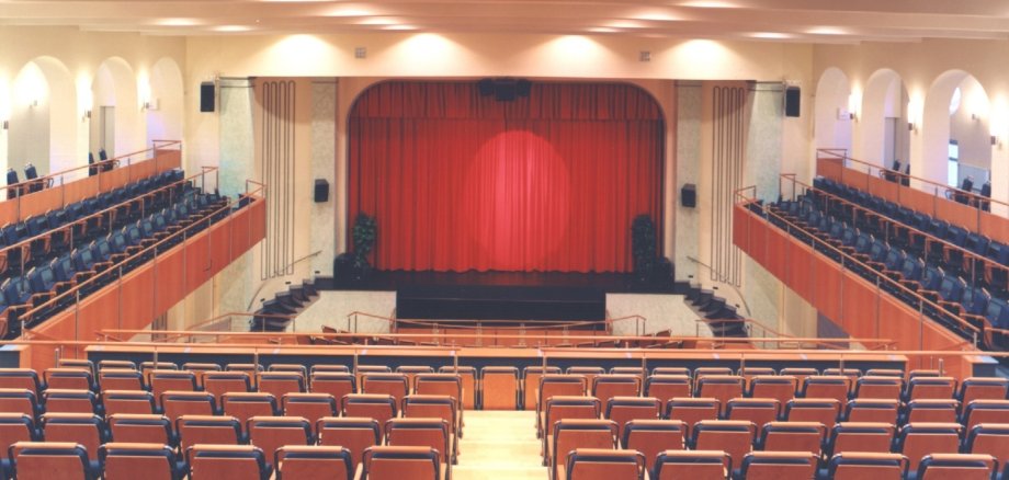 Das Foto zeigt einen Blick von der Zuschauertribüne auf die Bühne des Stadttheaters. Der Vorhang der Bühne ist geschlossen.