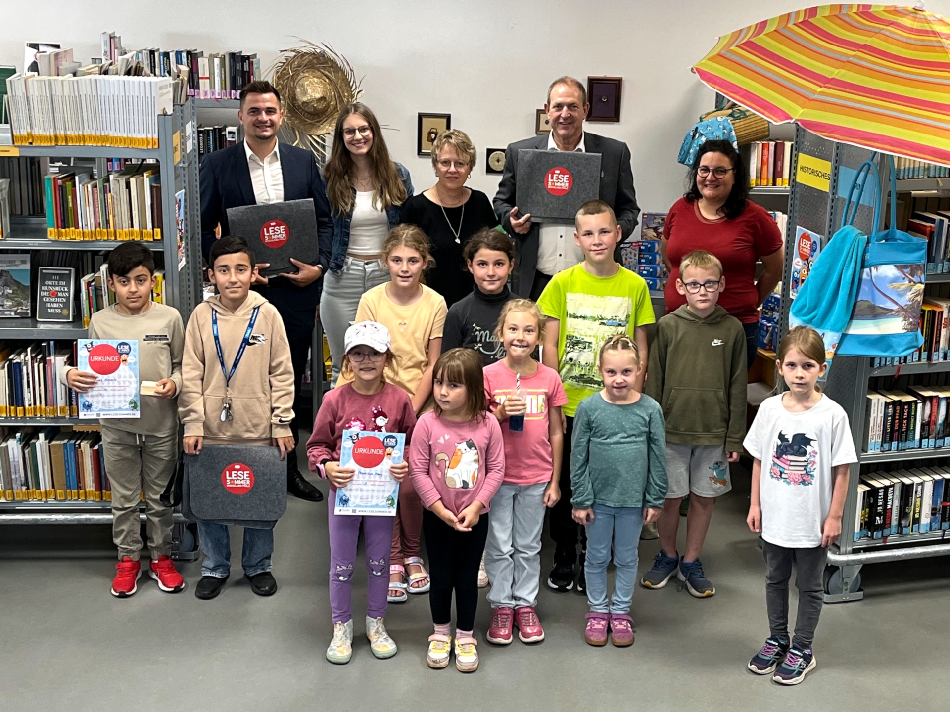 Das Foto zeigt OB Frühauf, Sandra Ley, ehrenamtliche Helferinnen, Niklas Jahke von der KSK Birkenfeld und Kinder in der Stadtbibliothek.