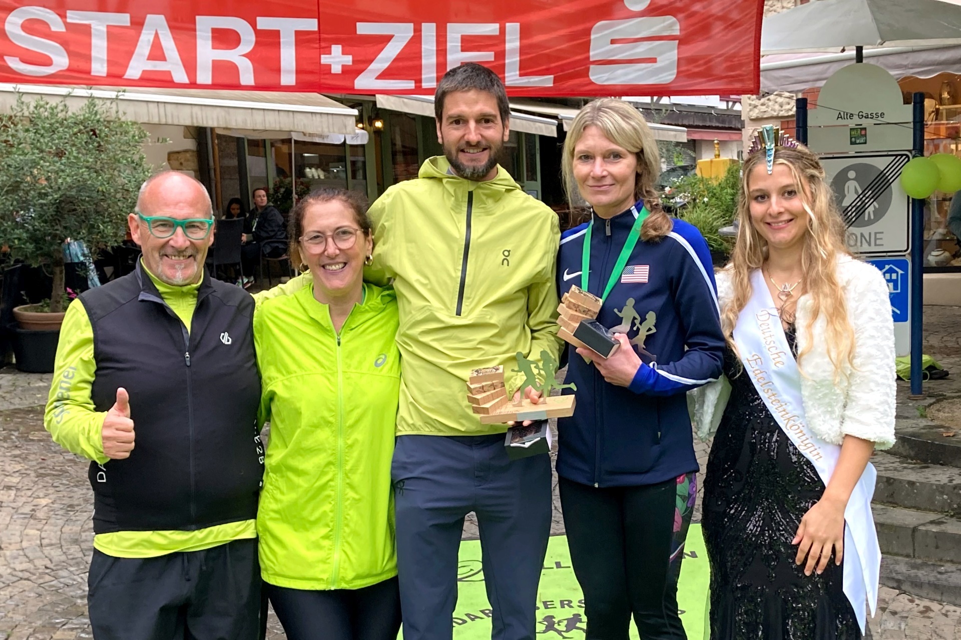 Das Foto zeigt die genannten Personen, die gemeinsam auf dem Siegerpodest stehen.