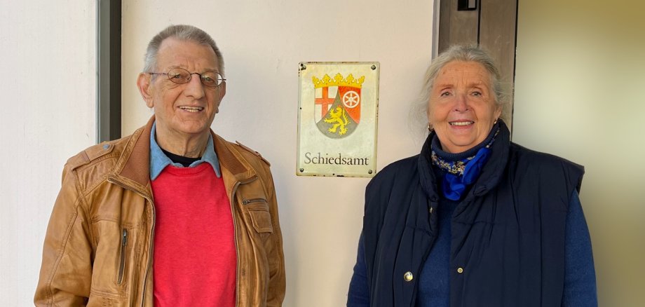 Das Foto zeigt die beiden Schiedspersonen vor dem Schild "Schiedsamt".