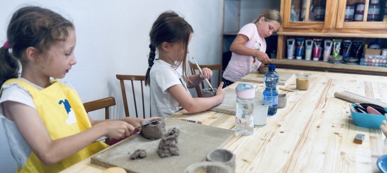 Im Töpferatelier konnten die Kinder getöpferte Kunstwerke gestalten und damit bleibende Erinnerungen mit nach Hause nehmen. Das Foto zeigt drei Mädchen beim Arbeiten mit Ton.