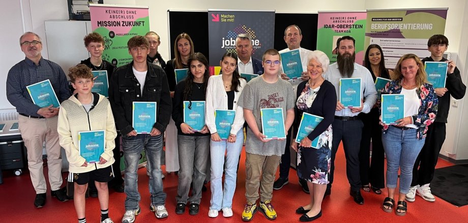 In der RS plus Idar-Oberstein wurde die neue Ausgabe der "jobzzone" vorgestellt. Das Foto zeigt die genannten Personen mit Schülerinnen und Schülern in einem Klassenraum der RS plus.