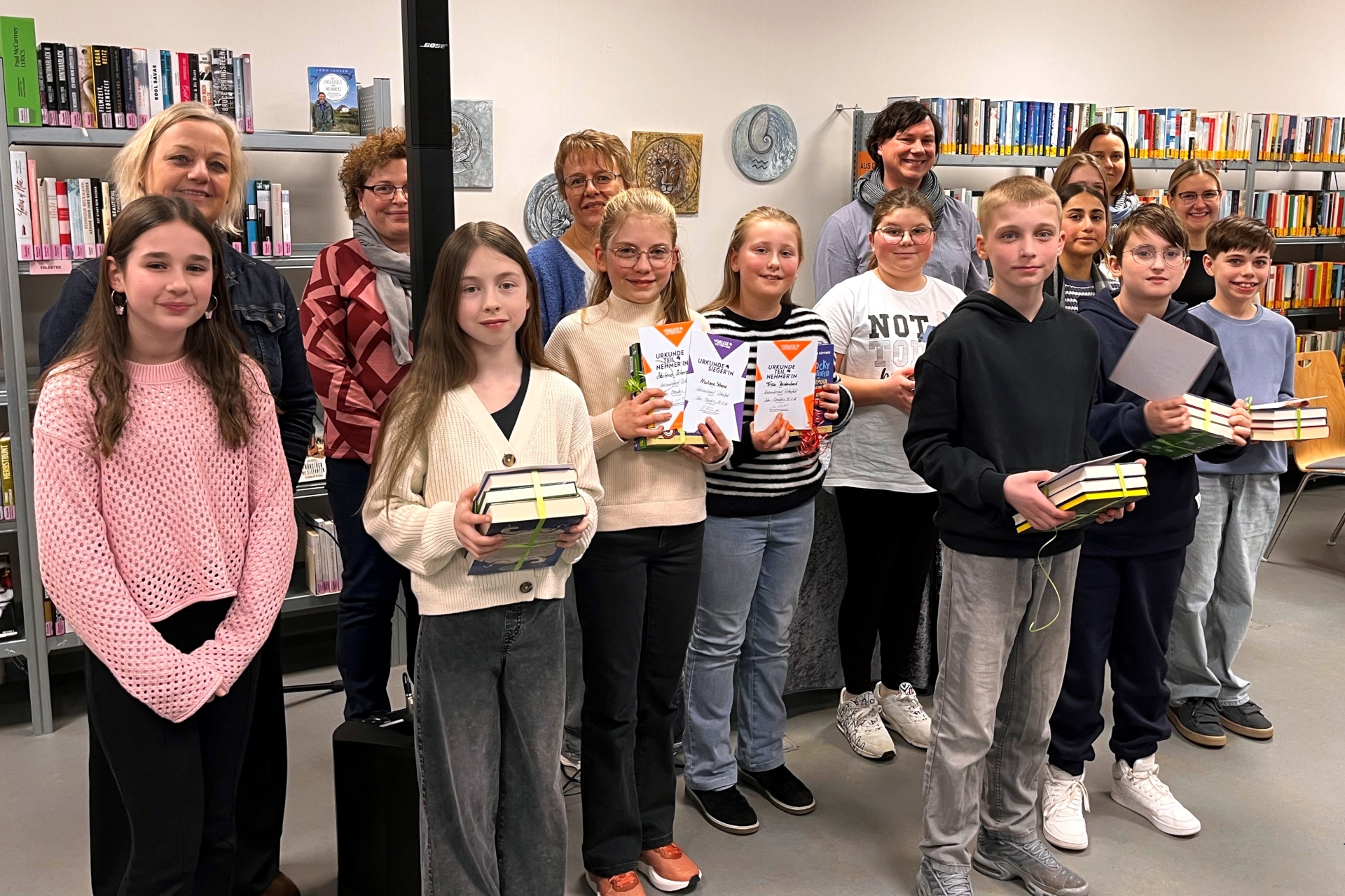 Das Gruppenfoto zeigt die genannten Personen in der Stadtbibliothek. Die Vorlesenden haben ihre Urkunden und Buchpräsente in den Händen.