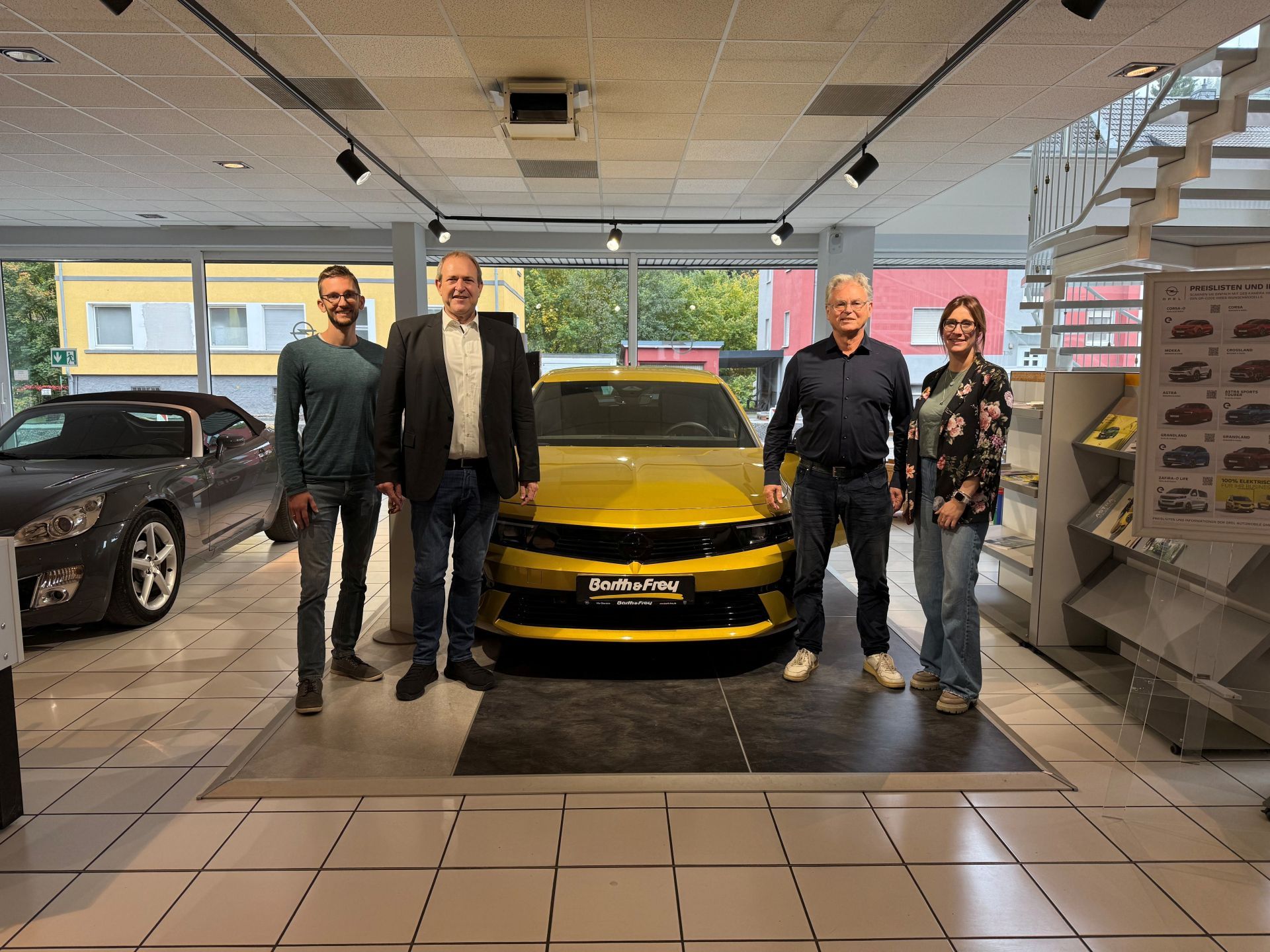 Das Foto zeigt die Firmeninhaber Michael und Moritz Frey, Oberbürgermeister Frühauf und Caroline Pehlke von der Wirtschaftsförderung neben einem Opel Fahrzeug. 