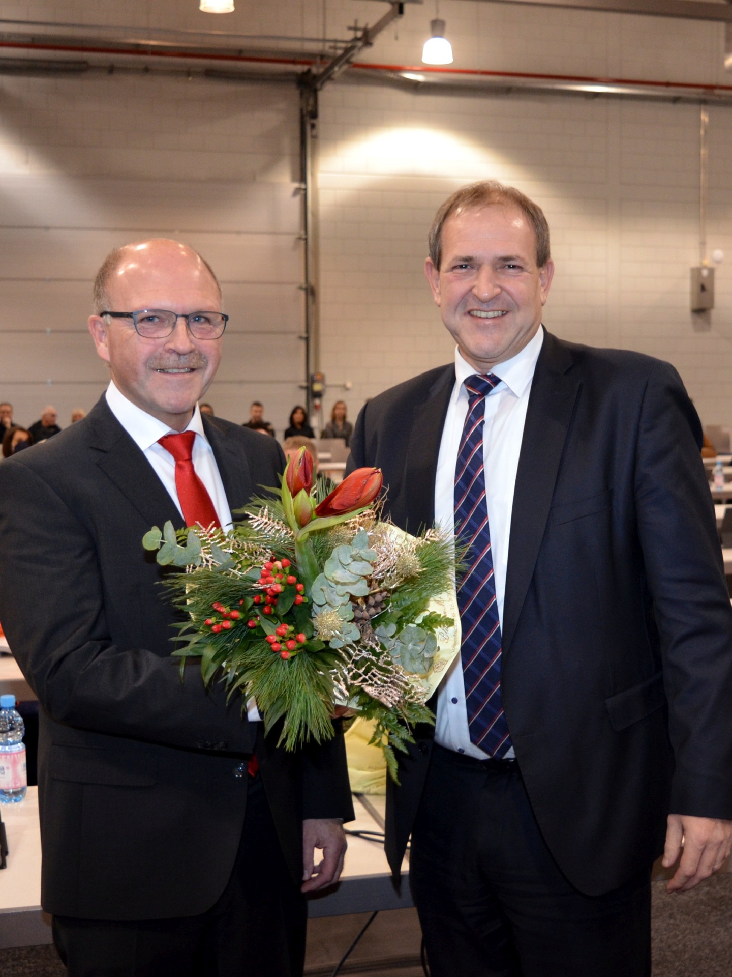 Das Foto zeigt die beiden Personen in der Messe Idar-Oberstein. OB Frühauf überreicht Bürgermeister Marx einen Blumenstrauß.