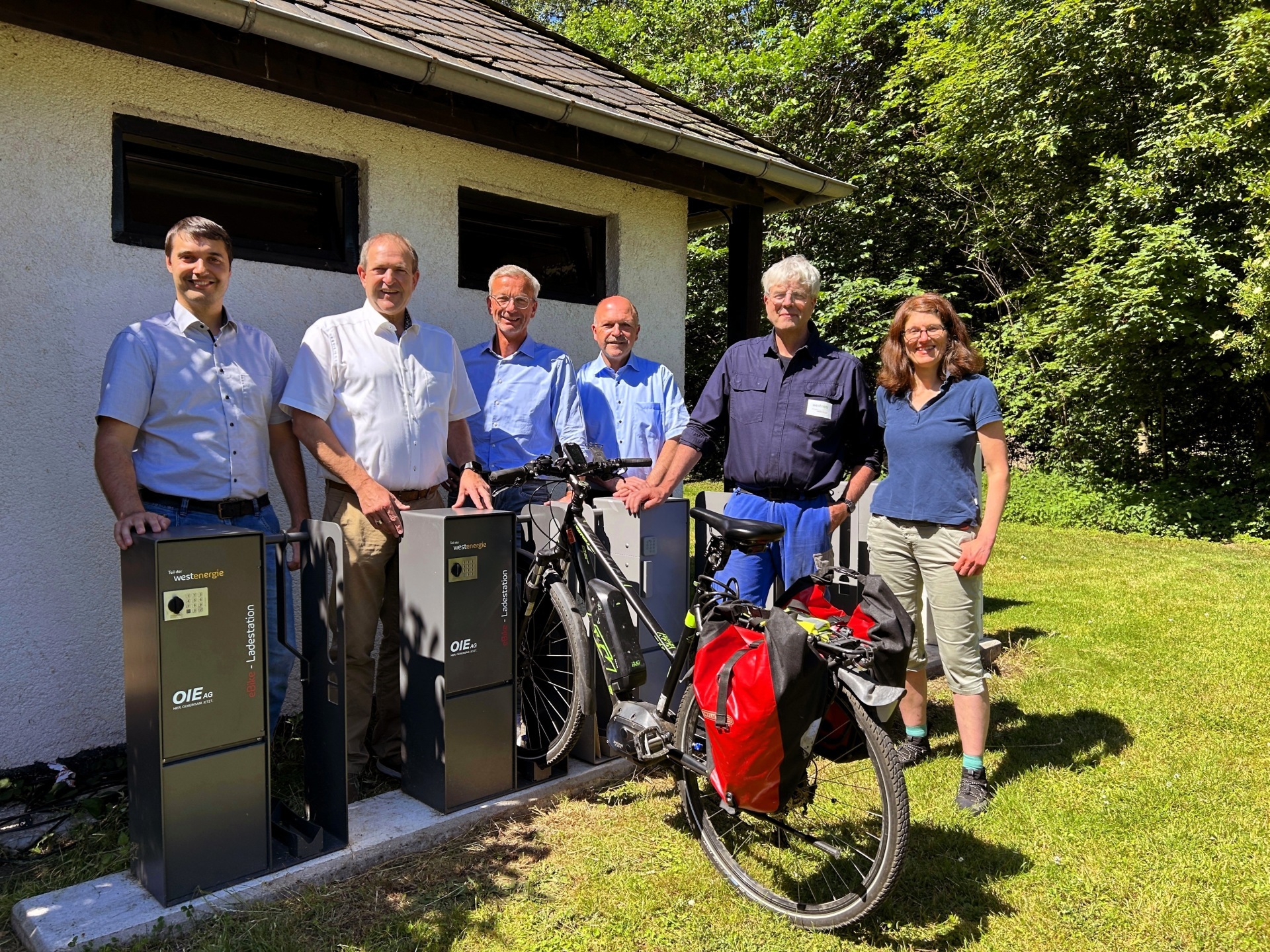 Das Foto zeigt die genannten Personen. Sie stehen hinter den neuen Ladesäulen an der Weiherschleife.